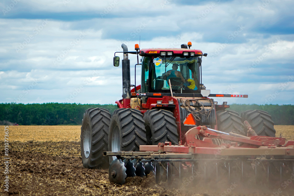 Fototapeta premium red tractor in a field rear view, tractor with a plow on an agricultural field. big red tractor working in the field, harvesting, business, agriculture. August 2020 Ukraine, Kiev region, editorial
