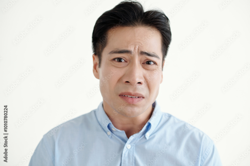 Portrait of young man with upset expression looking at camera on white background Portrait of young man with upset expression looking at camera on white background