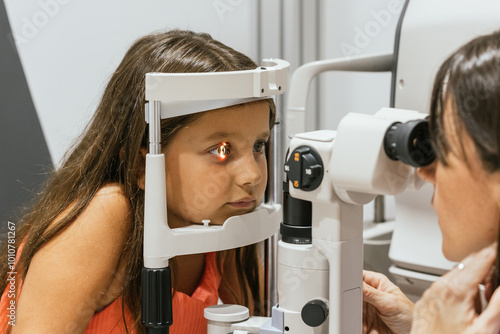 Fototapeta Optometrist examining little girl's vision with slit lamp