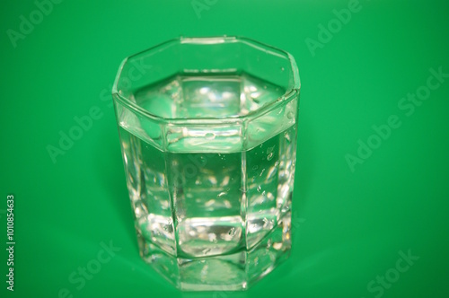 A glass of water on a green background.