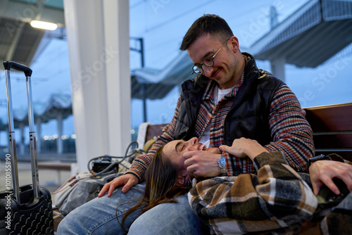 In the comfort of each others company, a couple engages in a playful conversation while waiting for their train, their connection evident.