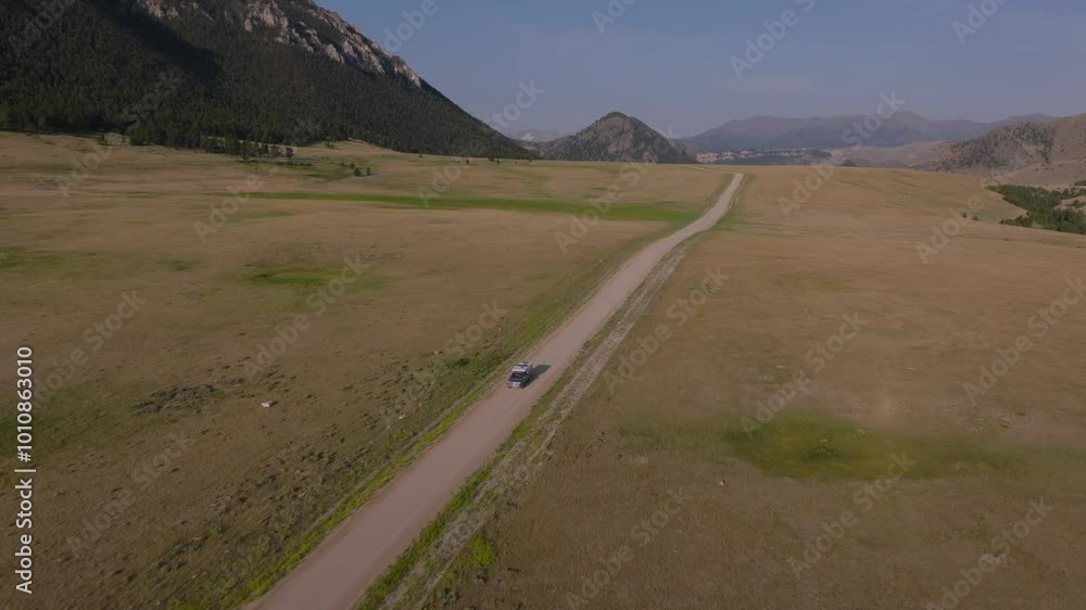 A camper drives through a vast open valley near mountains on Beartooth Highway in Wyoming A camper drives through a vast open valley near mountains on Beartooth Highway in Wyoming