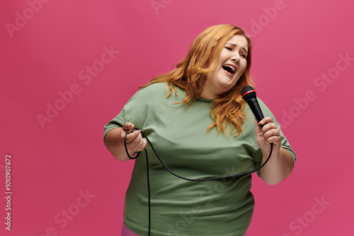 Joyful, plus-size woman in green shirt sings passionately into a microphone