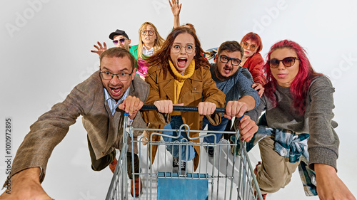 Group of super emotional and excited people pushing shopping cart forward with craziness. Competition for best deals. Concept of Black Friday, Cyber Monday, shopping photo