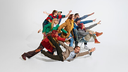 Group of emotional people, men in women pushing forward the best shopping deals, pushing shopping cart. Intensity of shopping activity. Concept of Black Friday, Cyber Monday, shopping