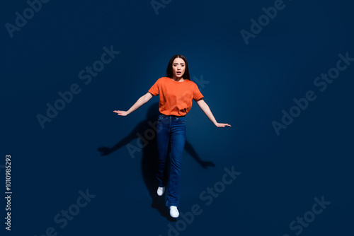 Photo of anxious embarrassed woman wear orange trendy clothes go empty space isolated on dark blue color background