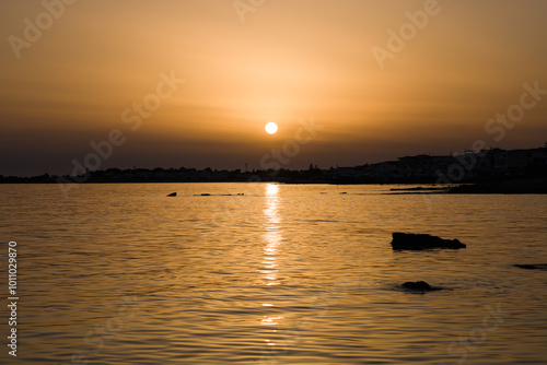 Tramonto a Marina di Ragusa con la costa e il faro di Puntasecca sullo sfondo photo