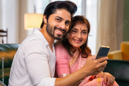Canvas Print Elderly Indian mother and son viewing photos or video calling on a smartphone in