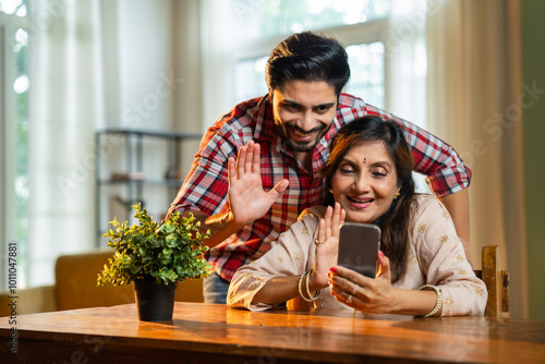 Photography Elderly Indian mother and son viewing photos or video calling on a smartphone in