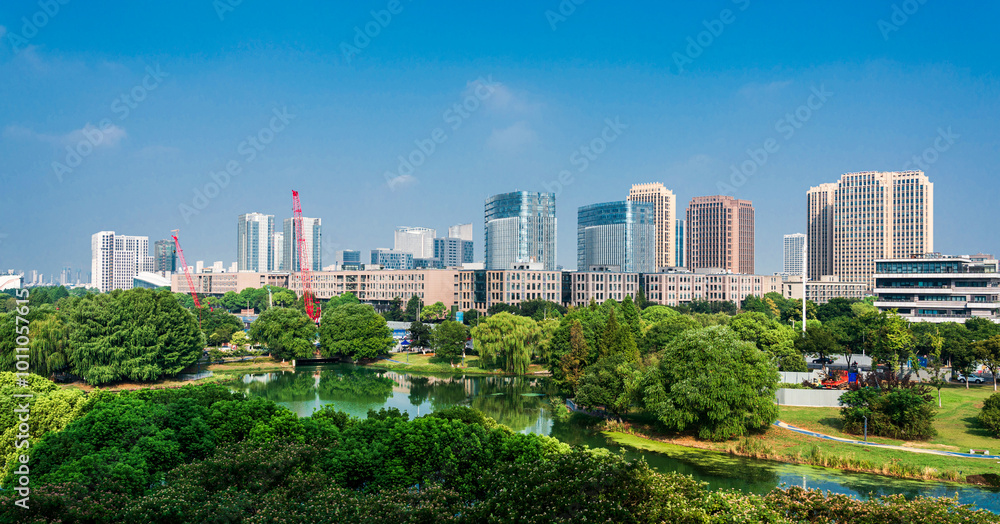 Obraz premium Vibrant City Skyline Surrounded by Lush Greenery at Daylight