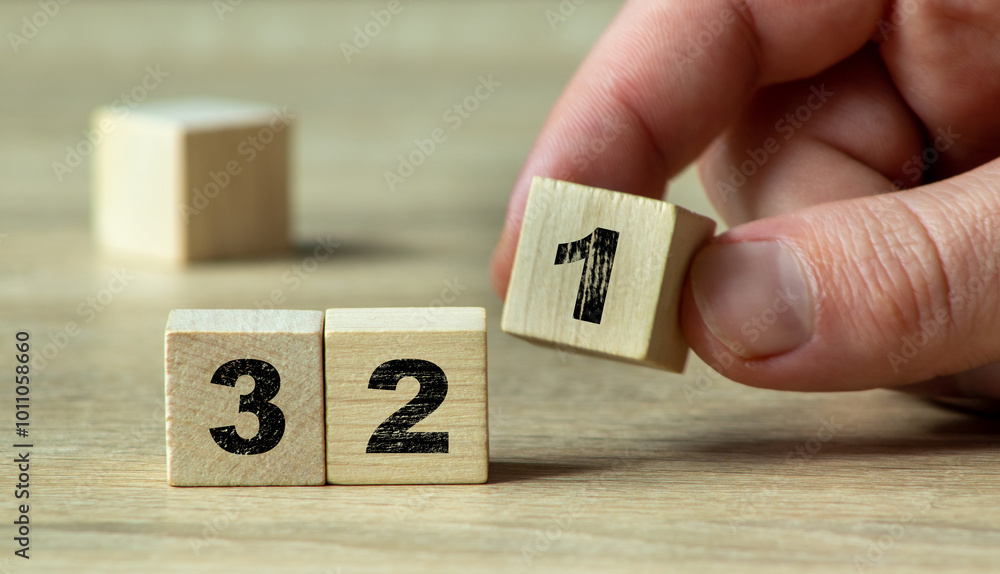 A hand holding a wooden block with the number 1 beside blocks with numbers 3 and 2, symbolizing counting or progress in a creative, minimalistic setting. A hand holding a wooden block with the number 1 beside blocks with numbers 3 and 2, symbolizing counting or progress in a creative, minimalistic setting.