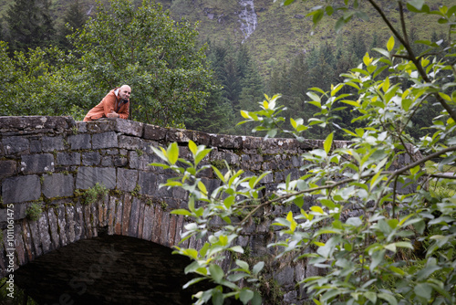 Scenic Green Landscape of Glen Shiel with Stone Bridge and Distant Man in the Scottish Highlands photo