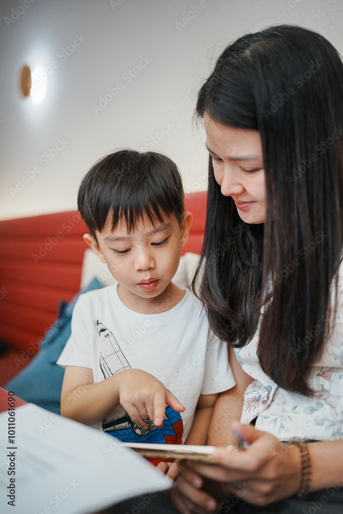 Mother and son bonding while using a tablet together indoors, enjoying quality time and digital learning in a cozy setting. Mother and son bonding while using a tablet together indoors, enjoying quality time and digital learning in a cozy setting.