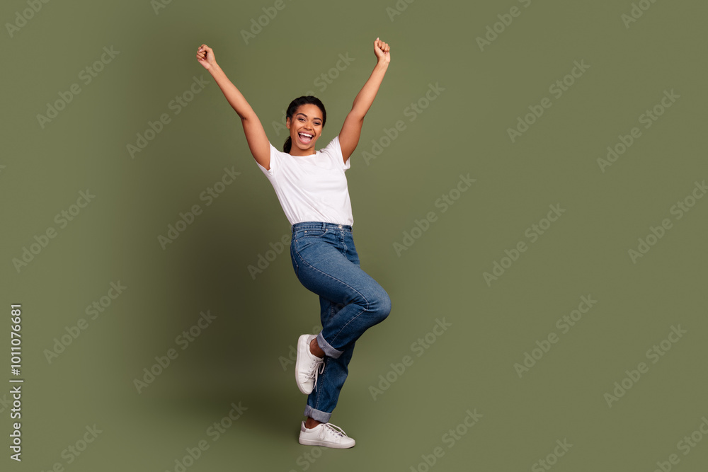 Full size photo of nice young woman raise fists empty space wear white t-shirt isolated on khaki color background Full size photo of nice young woman raise fists empty space wear white t-shirt isolated on khaki color background