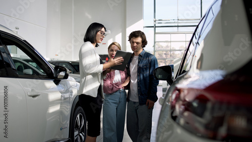 A married couple consults with a female dealer in a modern showroom about their options for a luxury car. This interaction showcases personalized service and expertise in the car-buying experience. photo