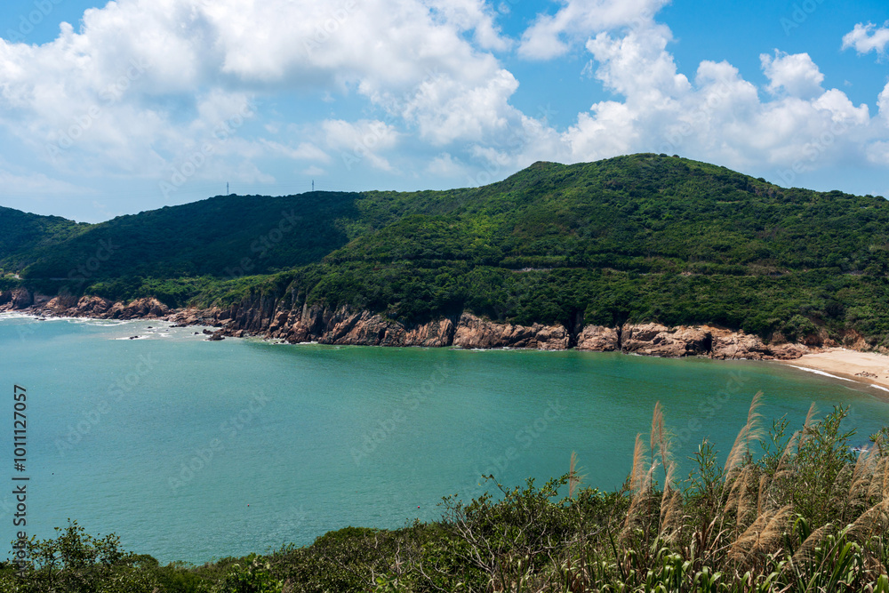 Serene Coastal Views: Lush Green Hills and Tranquil Waters Under a Blue Sky