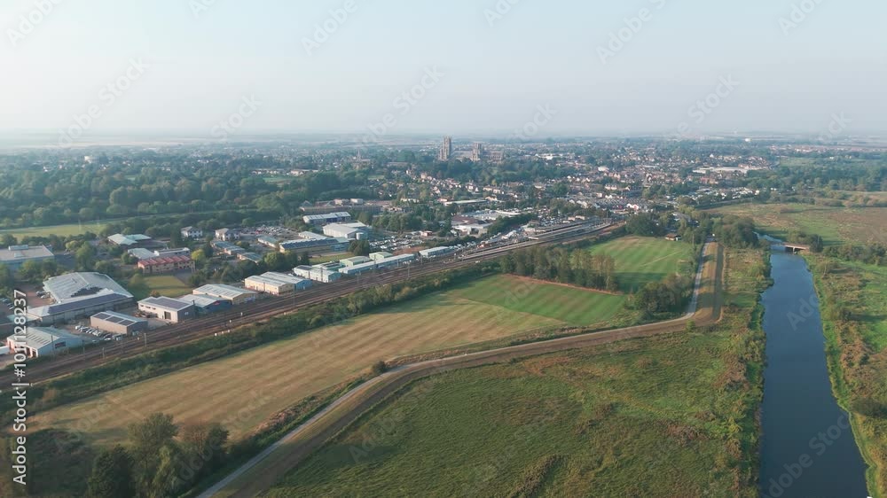 Aerial view of a town with buildings, roads, and a river bordered by fields and trees. The clear sky and horizon enhance the urban landscape Aerial view of a town with buildings, roads, and a river bordered by fields and trees. The clear sky and horizon enhance the urban landscape