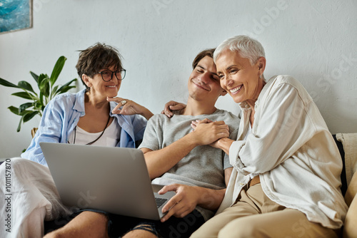 Lesbian parents and their adult son share laughter and joy while enjoying time together at home.