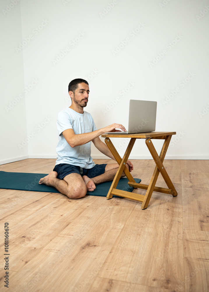 Caucasian Latino male performing a yoga session at home while following instructions from his laptop, combining technology and wellness. Caucasian Latino male performing a yoga session at home while following instructions from his laptop, combining technology and wellness.