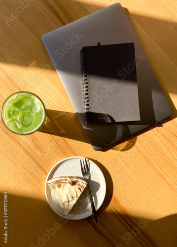 Serene workspace with matcha drink, dessert, and notebook.