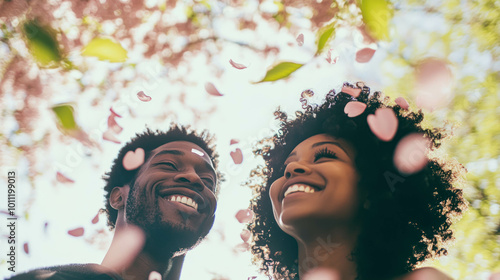 Portait Of A Happy Afro Couple During Spring Season, Cherry Blessom Petals And Green Leaves. Happy Couple Concept photo