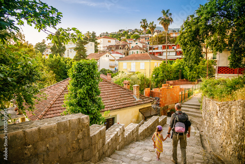 Schilderij op canvas A man and his little daughter walking down a stone stairway in a sunlit, hillsid