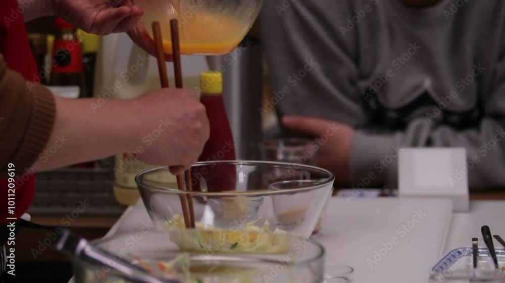 부엌에서 젓가락으로 달걀을 샐러드에 섞는 사람