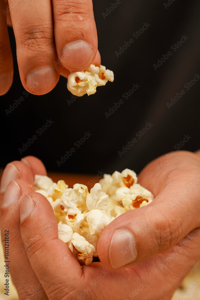 Delicious snack to eat in the cinema. Salted popcorn. Popcorn. Fast food. Junk food. Snack for cinema. Man holding popcorn to eat. Delicious snack to eat in the cinema. Salted popcorn. Popcorn. Fast food. Junk food. Snack for cinema. Man holding popcorn to eat.