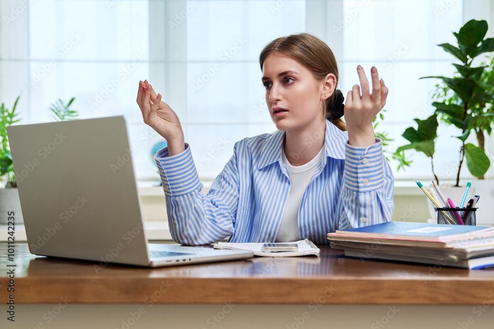 Teenage girl student studying online sitting at home at desk using laptop for video conference Teenage girl student studying online sitting at home at desk using laptop for video conference