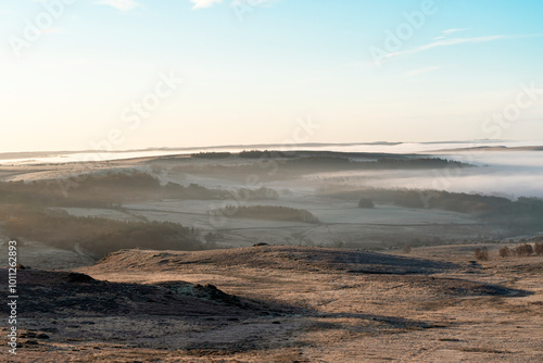 Stunning winter morning landscape with mist rolling over rolling hills and valleys in serene countryside