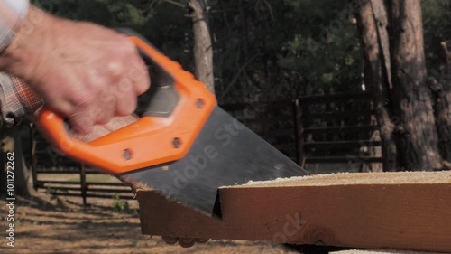 A person is using a hand saw to cut a piece of wood while surrounded by tall trees in a serene forest environment. The focus is on the precision of the sawing action.