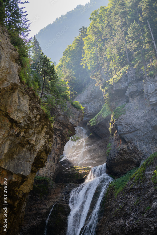 Scenic waterfall cascading down rocky cliffs in a lush mountain forest Scenic waterfall cascading down rocky cliffs in a lush mountain forest