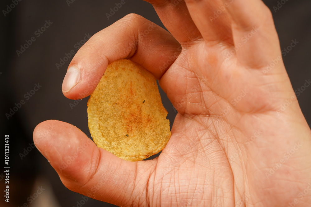 Unhealthy lifestyle. Man eating potato chips. Fast food. Junk food. Hands hold potato chip. Calories. Obesity. American food. Okay sign. Unhealthy lifestyle. Man eating potato chips. Fast food. Junk food. Hands hold potato chip. Calories. Obesity. American food. Okay sign.
