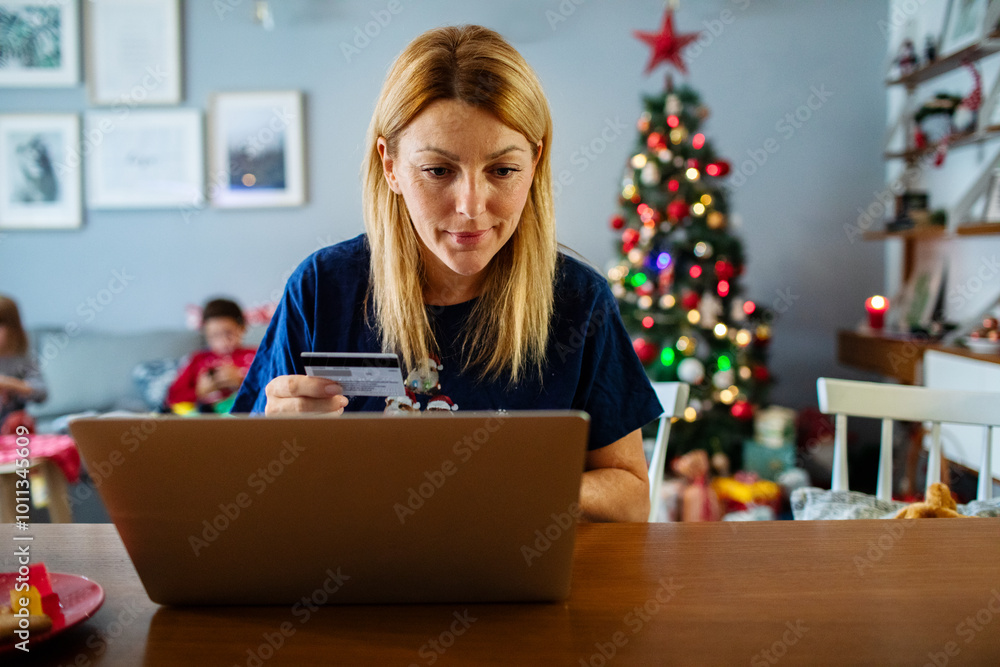 Woman doing Christmas shopping online using a credit card on laptop at home Woman doing Christmas shopping online using a credit card on laptop at home
