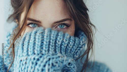 Photo of a beautiful woman in a blue sweater covering her face with her hands