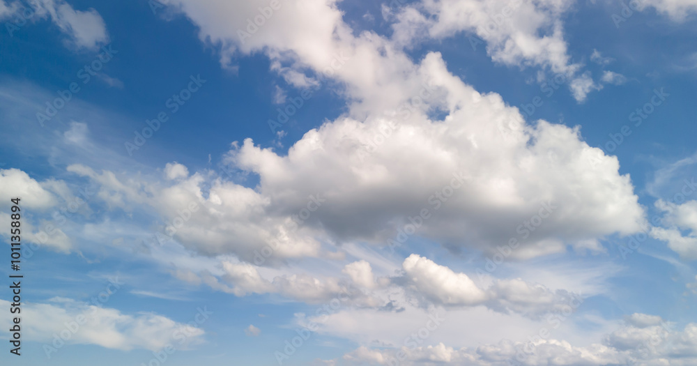 Fototapeta premium Beautiful blue sky with fluffy white clouds creating a serene atmosphere. Perfect for backgrounds, nature themes, or weather-related content.