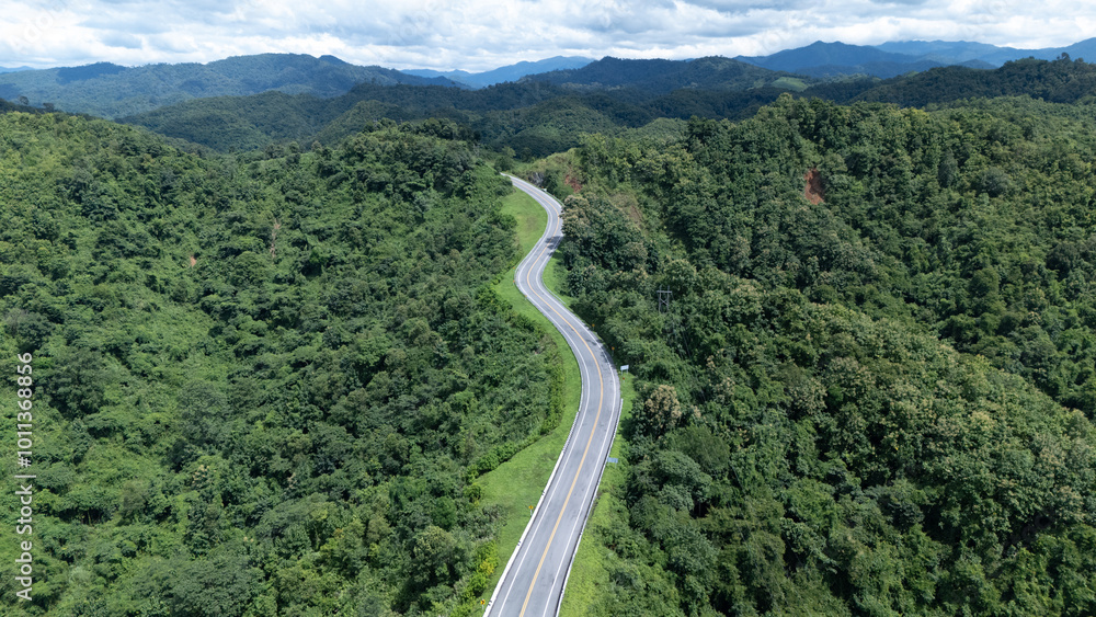 Aerial view from above of country road through the green summer forest in summer Thailand. Top view of the asphalt road and dense green forests.
Aerial view from above of country road through the green summer forest in summer Thailand. Top view of the asphalt road and dense green forests.
