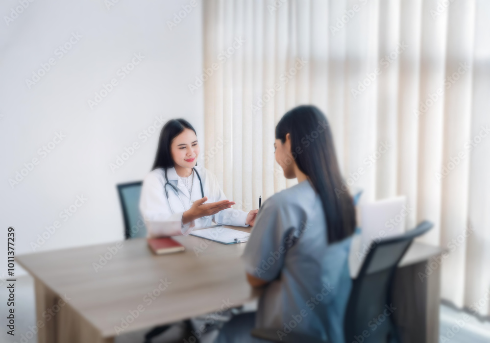 A female doctor in a white coat and stethoscope gestures while talking to a patient sitting across from her at a wooden desk. A female doctor in a white coat and stethoscope gestures while talking to a patient sitting across from her at a wooden desk.