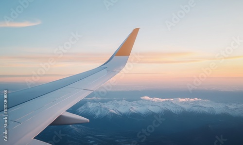 A Sunset View From an Airplane Wing Over Snow-Capped Mountains in the Distance