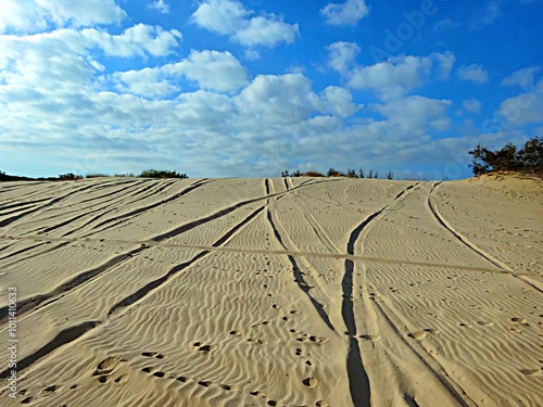 Footprints on sand dunes against the sky