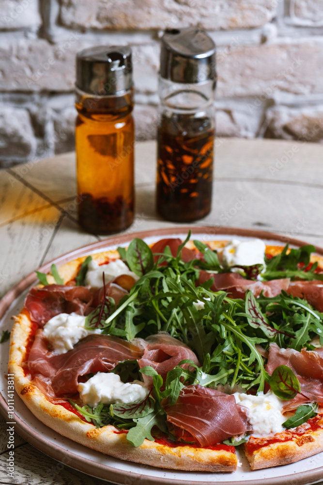 Pizza with prosciutto, arugula and cheese in wooden desk Pizza with prosciutto, arugula and cheese in wooden desk