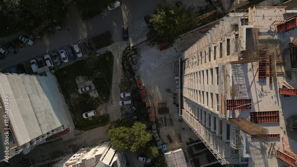 A drone video showcasing a top-down view of a construction site. The image captures the building's foundation, scaffolding, and materials, highlighting the early stages of architectural development A drone video showcasing a top-down view of a construction site. The image captures the building's foundation, scaffolding, and materials, highlighting the early stages of architectural development