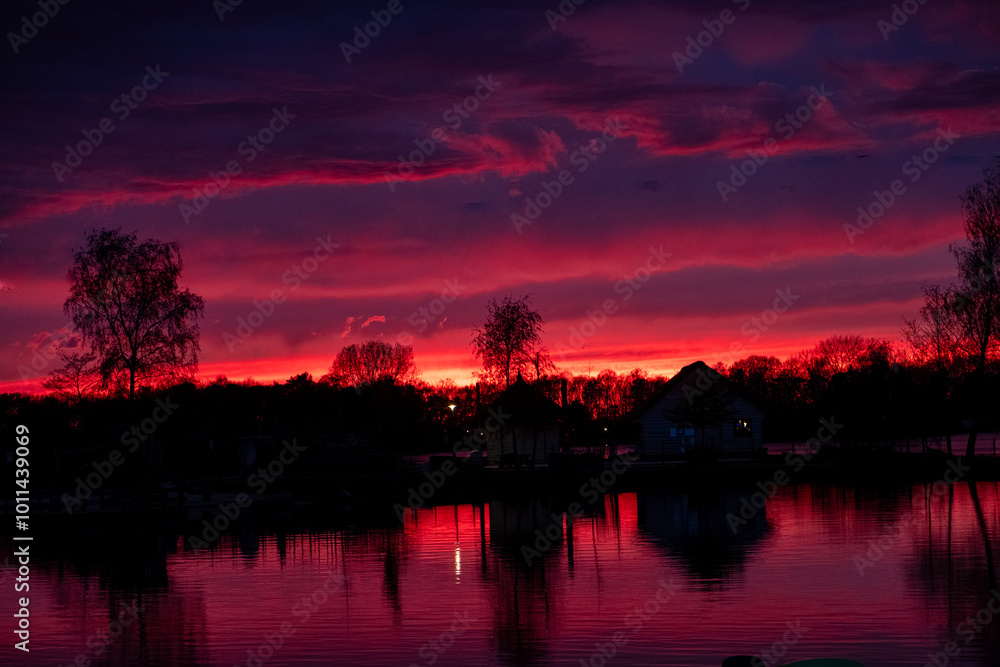 A stunning and breathtaking view of a vibrant sunset beautifully reflecting on a peaceful and calm lake A stunning and breathtaking view of a vibrant sunset beautifully reflecting on a peaceful and calm lake