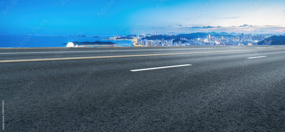 Fototapeta premium Scenic Highway Overlooking a Vibrant City Skyline and Ocean View at Dusk