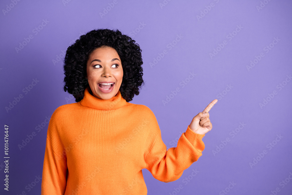 Photo of adorable excited girl wear orange jumper pointing looking empty space isolated violet color background Photo of adorable excited girl wear orange jumper pointing looking empty space isolated violet color background
