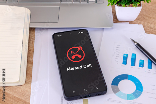 A mobile phone on a desk with a missed call notification on the phone screen
