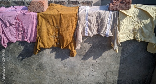 A colorful array of fabrics hanging to dry on a rooftop The fabrics are in various shades of pink orange beige and yellow and appear to be traditional garments