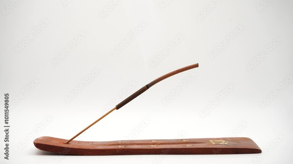 A smoking incense stick rests elegantly in a holder, isolated on a clean white background. This calming scene emphasizes relaxation and well-being, perfect for wellness and meditation themes A smoking incense stick rests elegantly in a holder, isolated on a clean white background. This calming scene emphasizes relaxation and well-being, perfect for wellness and meditation themes