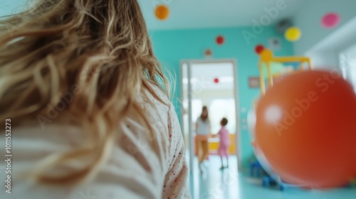 A young girl looks on as another child plays across the colorful, engaging playroom, embodying moments of observation, wonder, and social interaction. photo