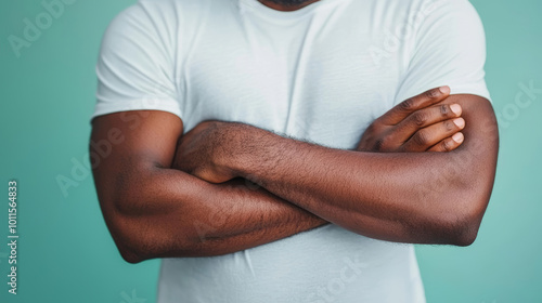 A young man stands with crossed arms, exuding confidence in a casual setting. His relaxed posture and neutral expression convey a sense of thoughtfulness.